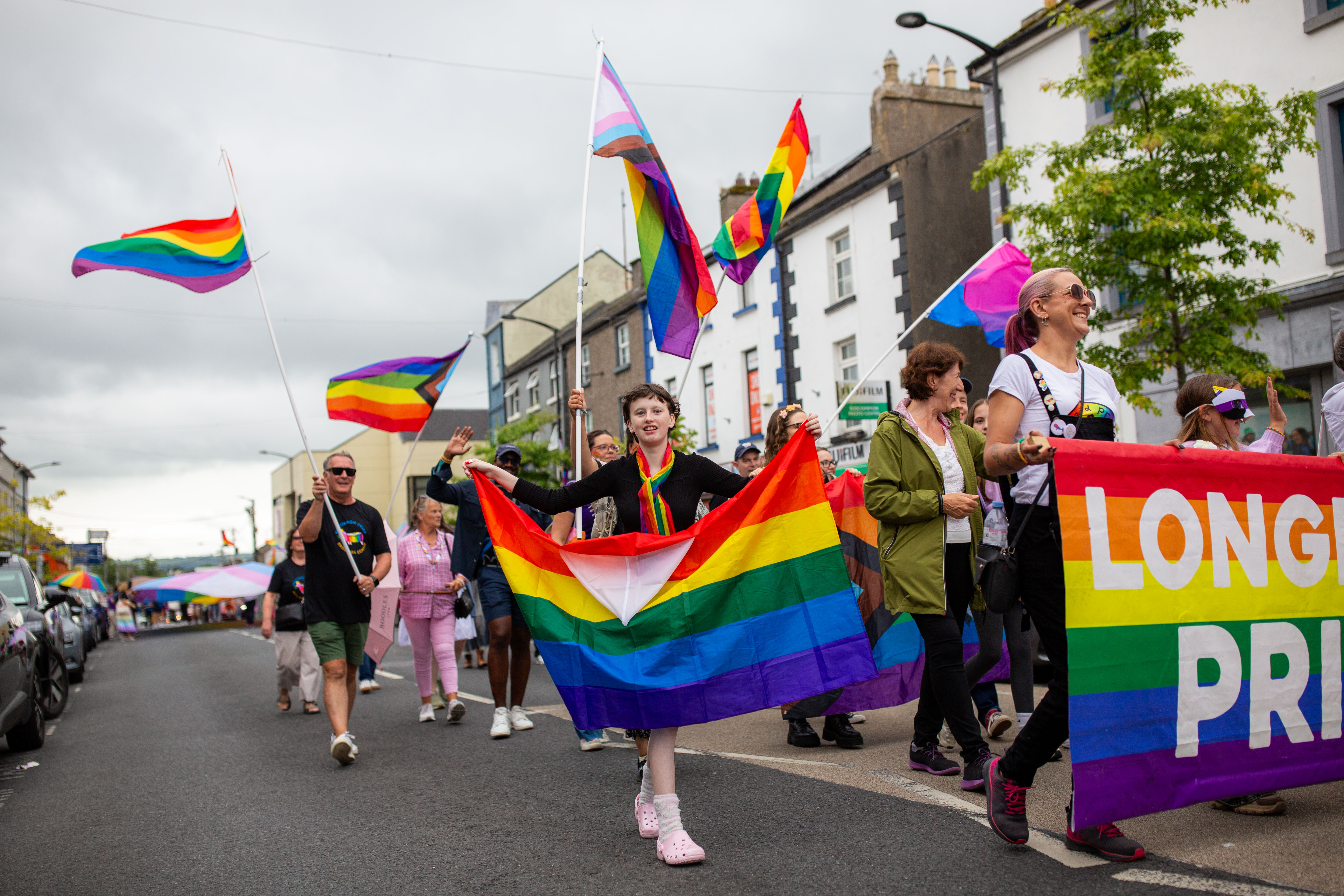 A lively Pride march featuring diverse participants holding rainbow flags and banners.